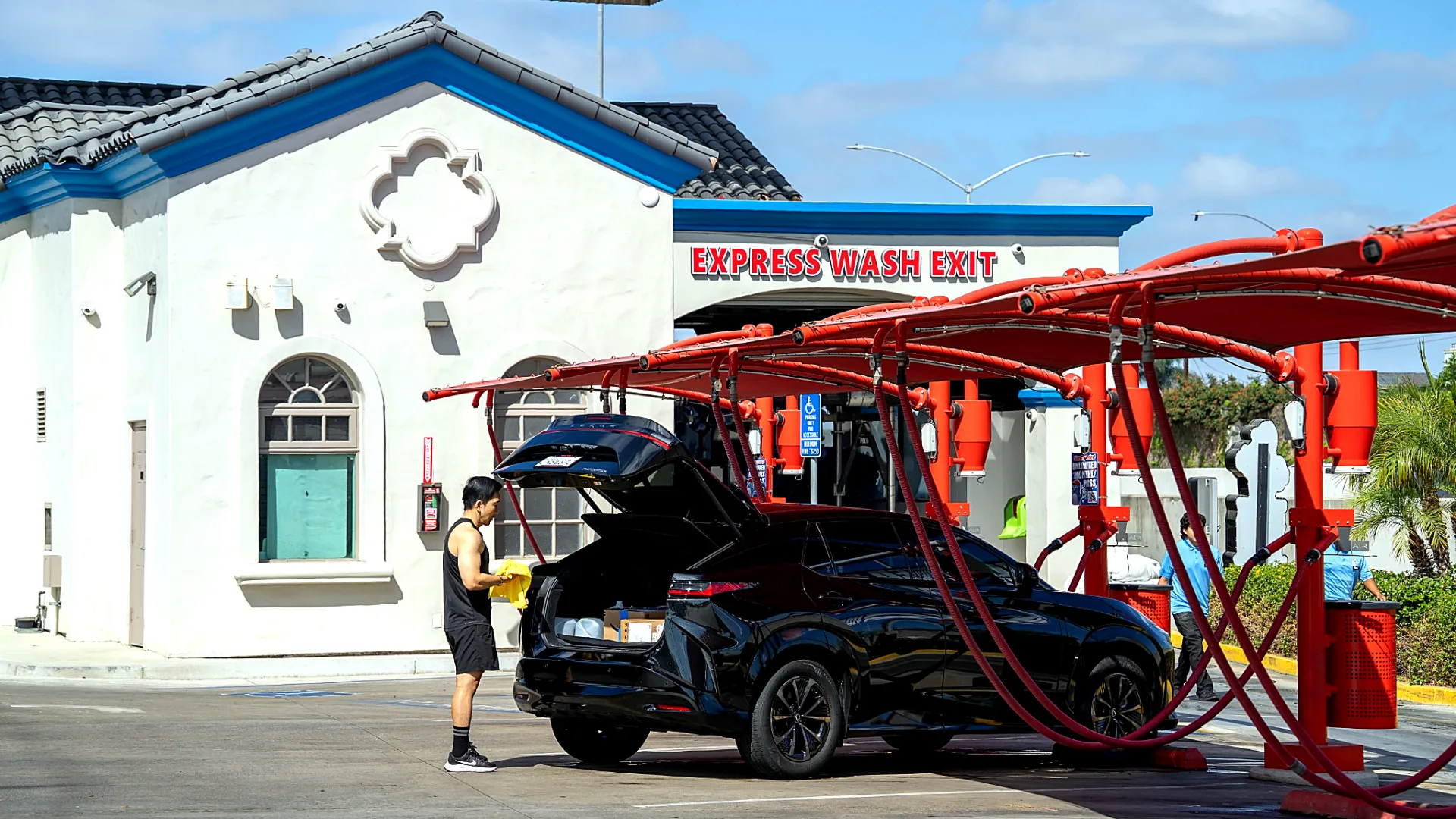 Customer drying their car at the free vacuum bay by the Seal Shine Express Car Wash express wash exit