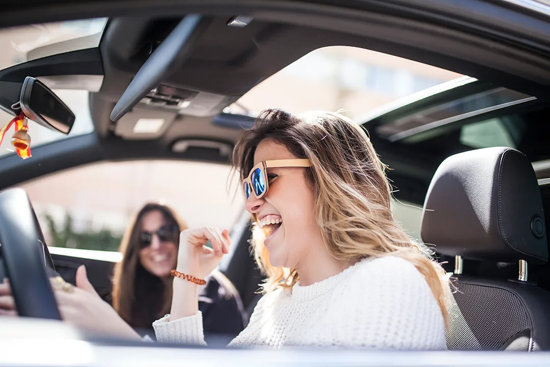 Friends laughing in a clean car enjoying Seal Shine Express Car Wash unlimited membership in Garden Grove